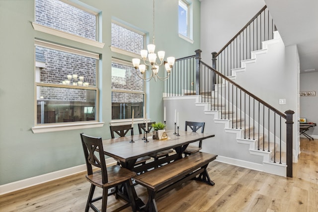 dining area featuring light wood-type flooring, an inviting chandelier, and a high ceiling