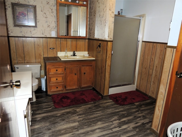 bathroom with toilet, vanity, wood walls, wood-type flooring, and a shower with shower door