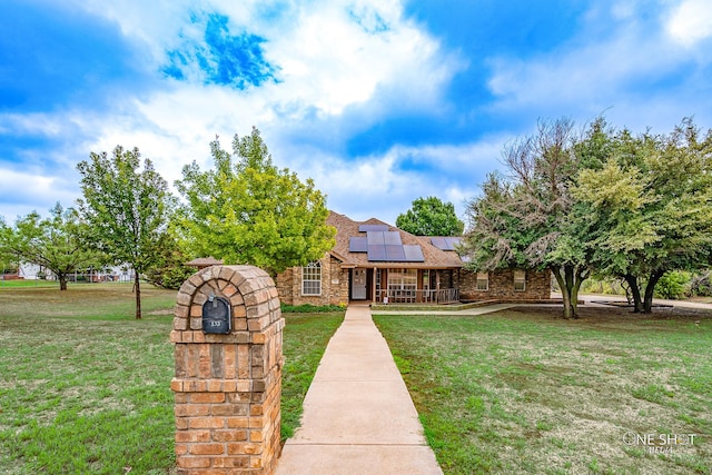 view of front of property with a front yard and solar panels