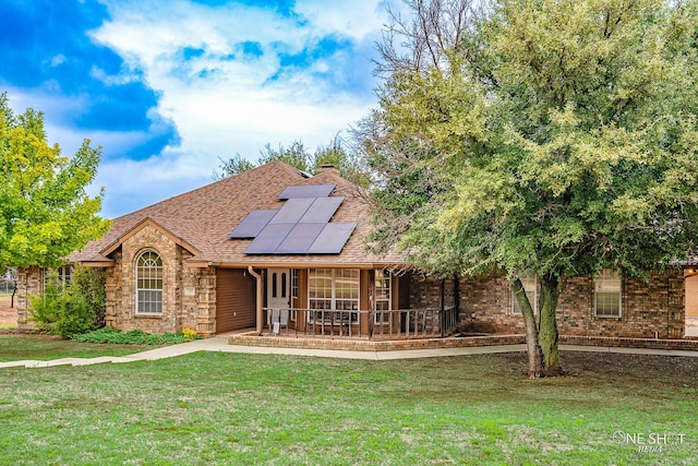 view of front facade with a porch, a front yard, and solar panels