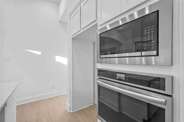 kitchen featuring white cabinets, light wood-type flooring, and stainless steel appliances