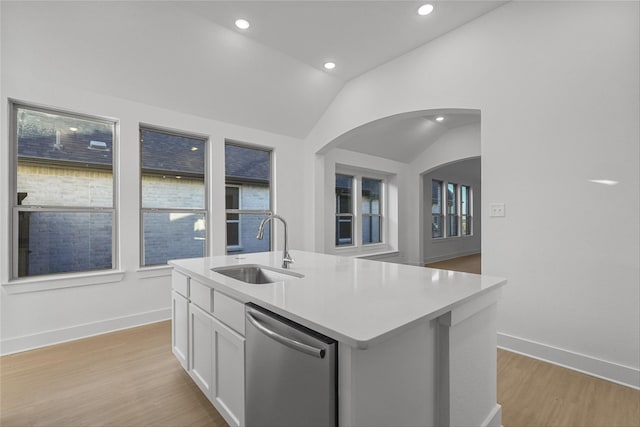 kitchen featuring white cabinets, vaulted ceiling, a kitchen island with sink, sink, and dishwasher