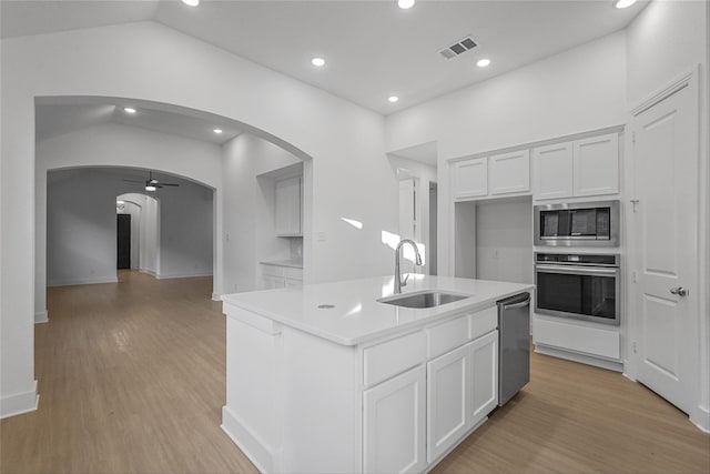 kitchen with stainless steel appliances, sink, light hardwood / wood-style flooring, white cabinets, and an island with sink