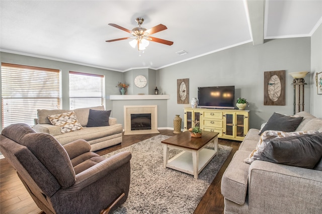 living room with a tiled fireplace, wood-type flooring, ceiling fan, and vaulted ceiling with beams