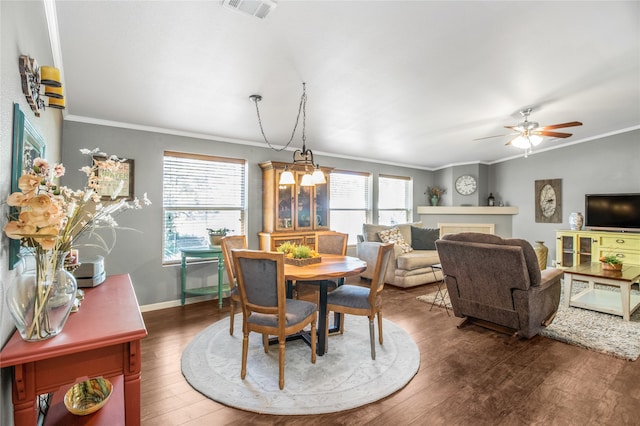 dining area featuring ceiling fan with notable chandelier, dark hardwood / wood-style flooring, and ornamental molding