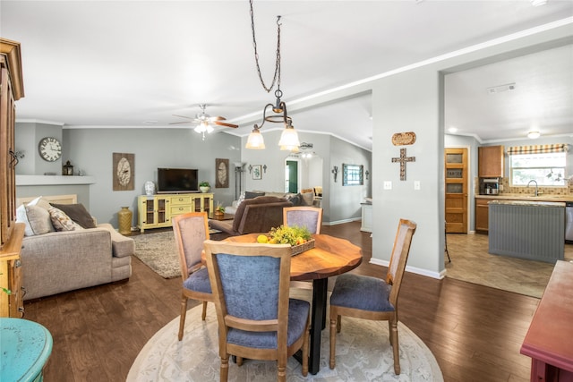 dining area with crown molding, dark wood-type flooring, sink, and ceiling fan