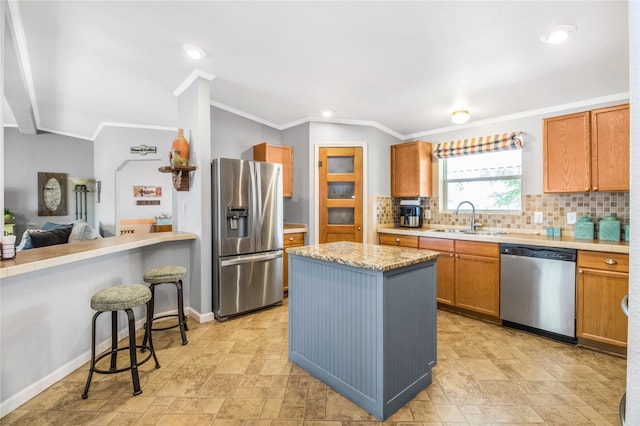 kitchen featuring appliances with stainless steel finishes, sink, decorative backsplash, ornamental molding, and a breakfast bar