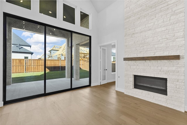 unfurnished living room featuring high vaulted ceiling, hardwood / wood-style flooring, and a stone fireplace