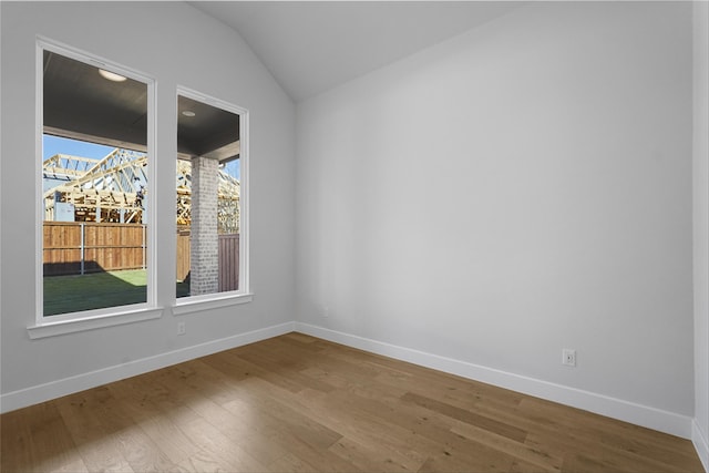 unfurnished room featuring wood-type flooring and vaulted ceiling