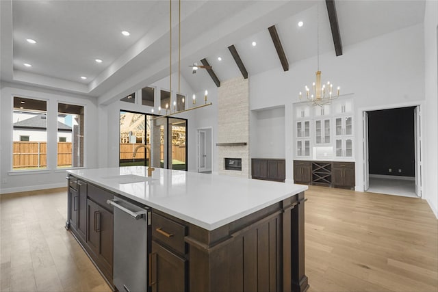 kitchen featuring decorative light fixtures, sink, a kitchen island with sink, and light hardwood / wood-style flooring