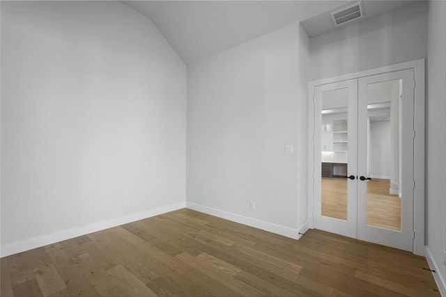 spare room with wood-type flooring, french doors, and lofted ceiling