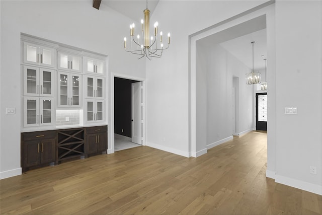 unfurnished dining area with a chandelier, hardwood / wood-style flooring, and high vaulted ceiling