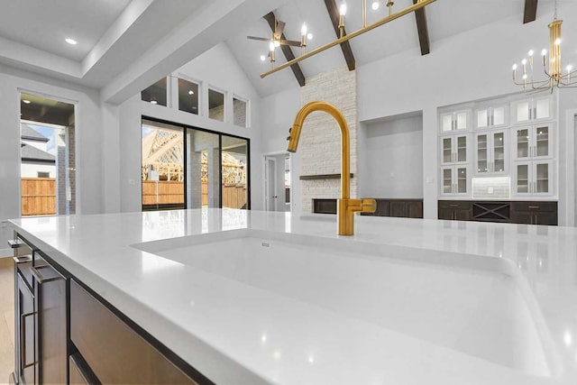 kitchen with a large fireplace, sink, pendant lighting, beam ceiling, and high vaulted ceiling