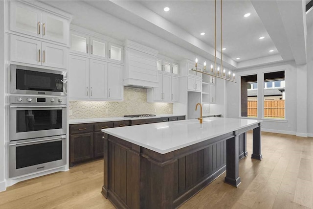 kitchen featuring sink, light hardwood / wood-style flooring, an island with sink, and appliances with stainless steel finishes