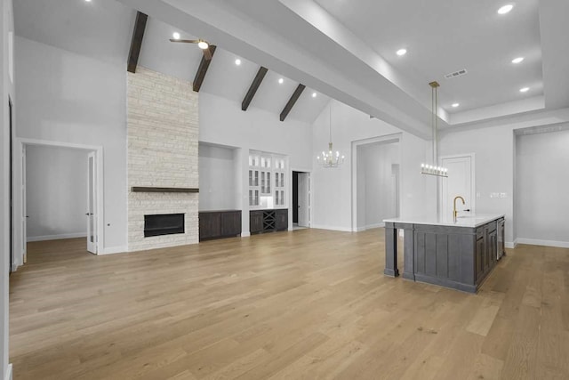 unfurnished living room featuring a stone fireplace, high vaulted ceiling, and light wood-type flooring