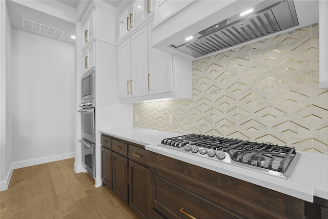 kitchen with gas cooktop, tasteful backsplash, white cabinets, and custom exhaust hood