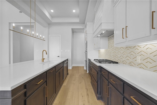 kitchen featuring sink, light hardwood / wood-style flooring, pendant lighting, white cabinets, and appliances with stainless steel finishes