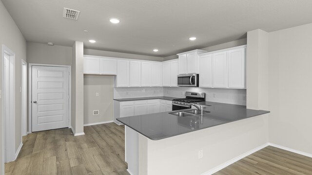 kitchen with kitchen peninsula, appliances with stainless steel finishes, light wood-type flooring, and white cabinetry