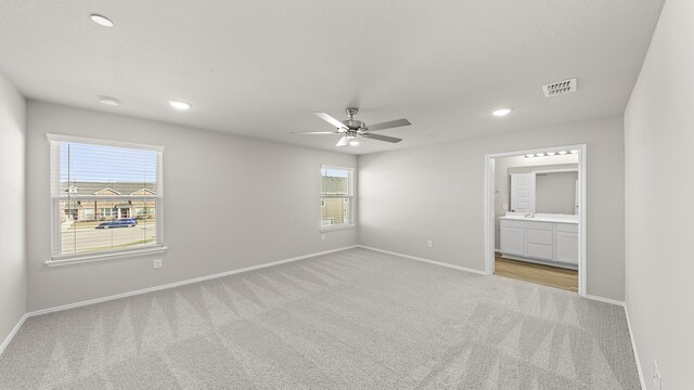 unfurnished bedroom with connected bathroom, ceiling fan, and light carpet