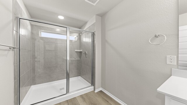 bathroom with wood-type flooring, vanity, and a shower with door