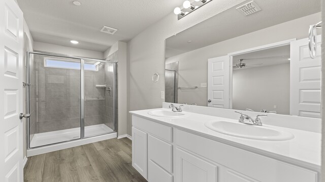 bathroom featuring walk in shower, vanity, a textured ceiling, ceiling fan, and hardwood / wood-style floors