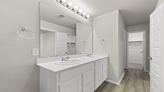 bathroom featuring hardwood / wood-style flooring, vanity, and a textured ceiling