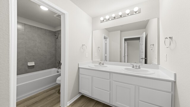 full bathroom with hardwood / wood-style flooring, vanity, toilet, and tiled shower / bath