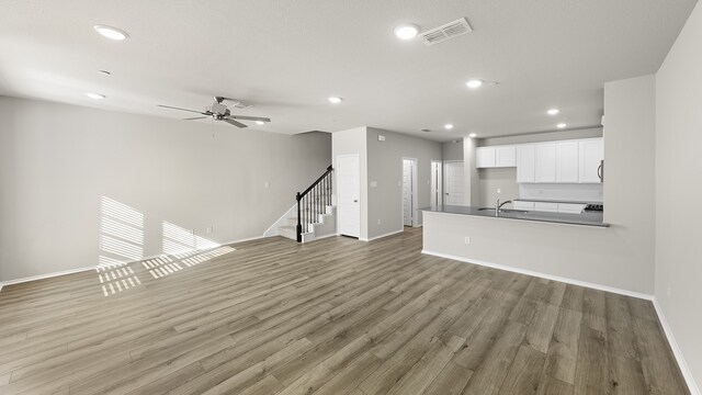 unfurnished living room featuring ceiling fan, sink, and wood-type flooring