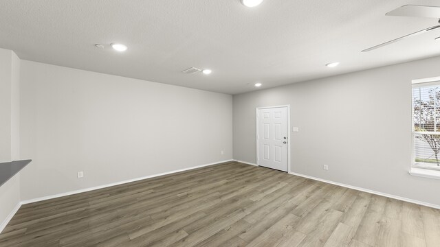 unfurnished room with a textured ceiling, hardwood / wood-style flooring, and ceiling fan