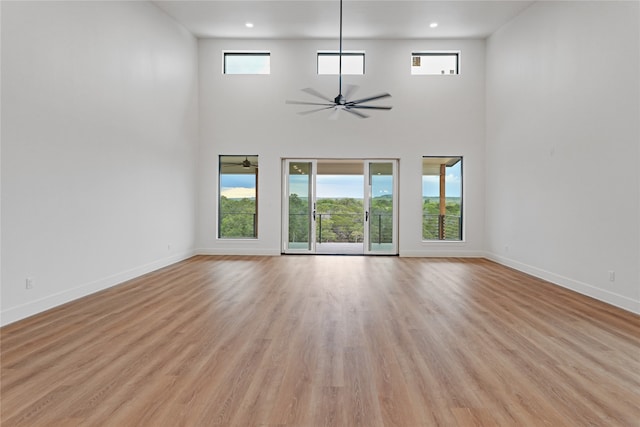 unfurnished living room with ceiling fan, light wood-style flooring, and baseboards