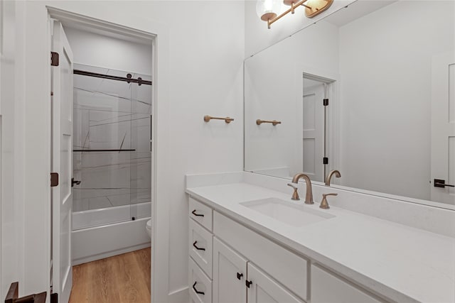 bathroom with toilet, bath / shower combo with glass door, wood finished floors, and vanity