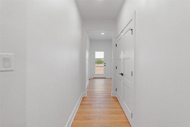 corridor featuring light wood-type flooring and baseboards