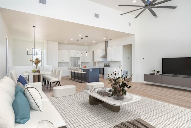 living area featuring light wood finished floors, recessed lighting, visible vents, and a notable chandelier