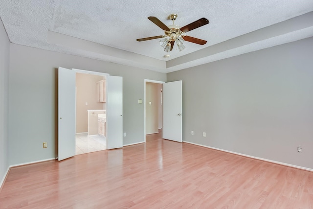 unfurnished bedroom featuring ceiling fan, light hardwood / wood-style floors, ensuite bath, and a textured ceiling