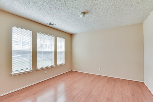 empty room with hardwood / wood-style flooring and a textured ceiling