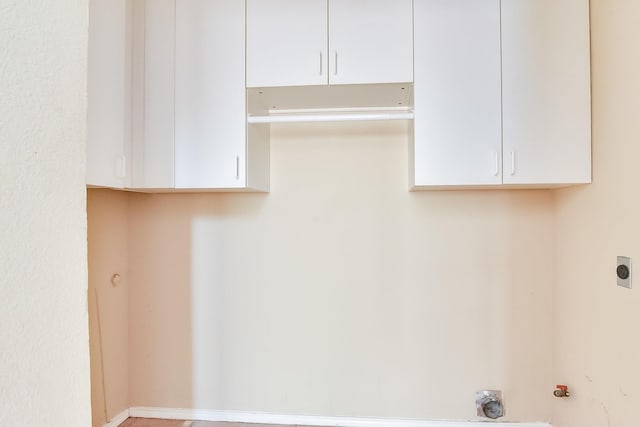 clothes washing area featuring hookup for an electric dryer and cabinets