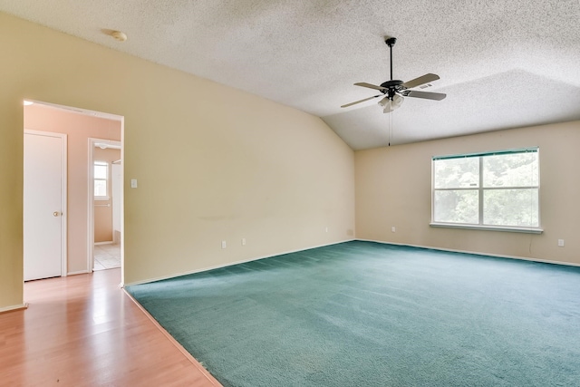 empty room with vaulted ceiling, a textured ceiling, ceiling fan, and carpet