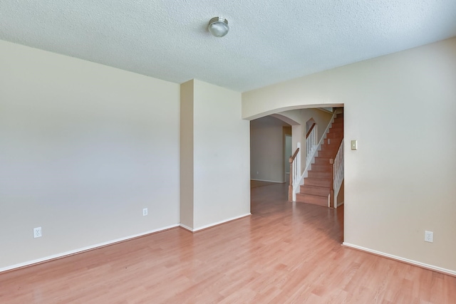 spare room featuring a textured ceiling and light hardwood / wood-style flooring