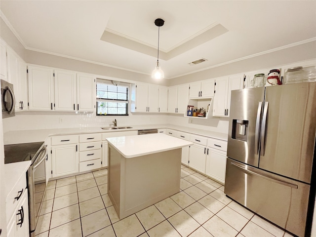 kitchen with light tile patterned floors, a kitchen island, a tray ceiling, appliances with stainless steel finishes, and white cabinets