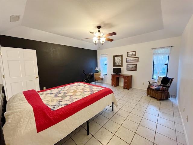 bedroom featuring ceiling fan, a raised ceiling, and light tile patterned flooring