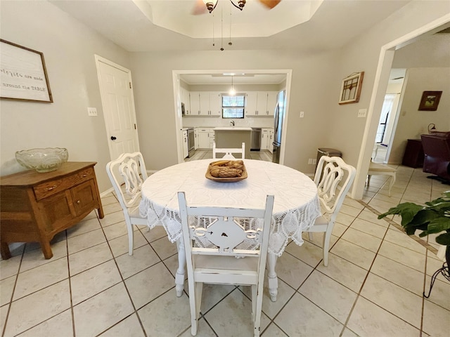 dining area featuring light tile patterned floors and a raised ceiling