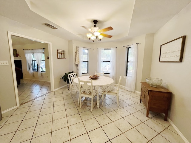 dining space with ceiling fan, a wealth of natural light, a raised ceiling, and light tile patterned flooring