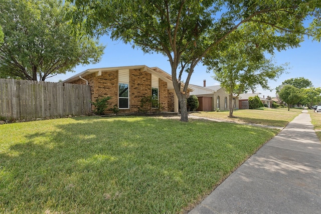 mid-century home with brick siding, a front lawn, and fence