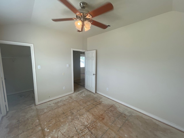 unfurnished bedroom with lofted ceiling, a walk in closet, ceiling fan, and a closet