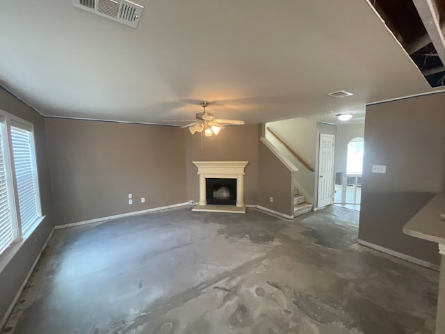 unfurnished living room featuring a healthy amount of sunlight, concrete flooring, and ceiling fan