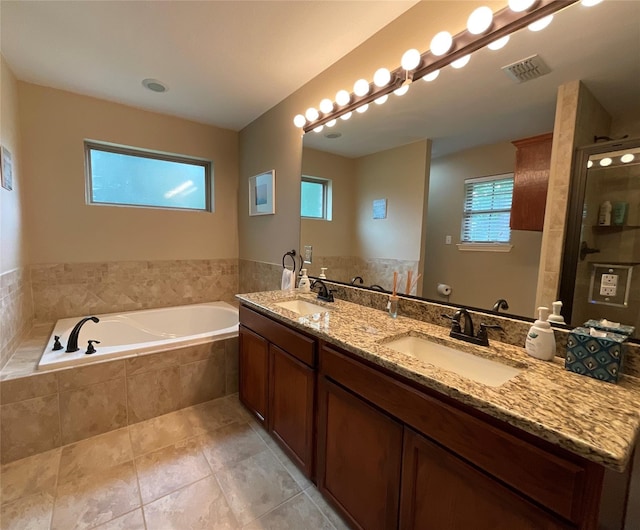 bathroom with tile patterned flooring, vanity, and tiled tub