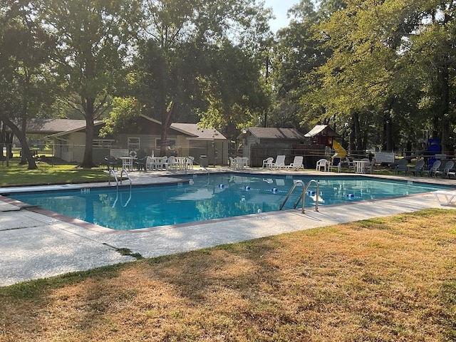 view of pool with a lawn and a patio