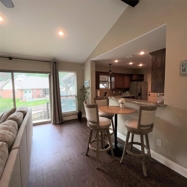 dining space with dark hardwood / wood-style flooring and vaulted ceiling