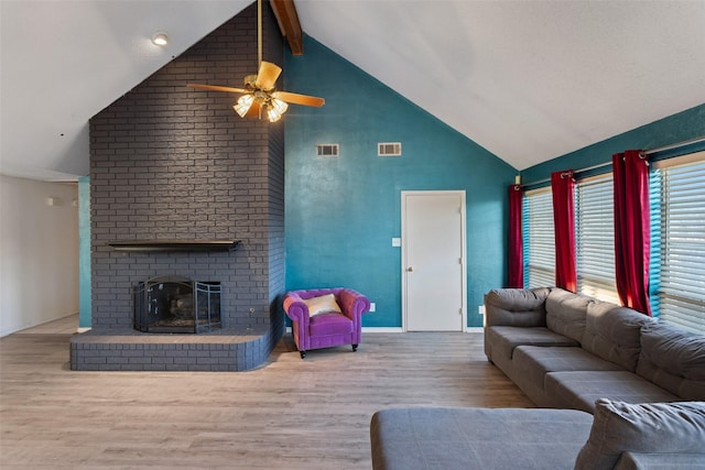 living room featuring ceiling fan, light wood-type flooring, a brick fireplace, and lofted ceiling with beams