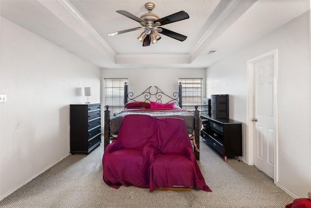 bedroom featuring ceiling fan, a tray ceiling, crown molding, and light carpet